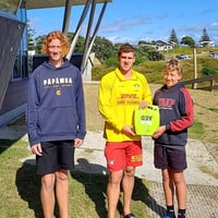 Mark Weedon’s sons Jack (left) and Rory (right) hand over the external AED defib unit to Pāpāmoa lifeguard Jake Cowdrey.
